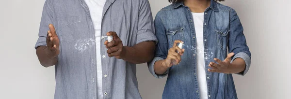 Prevenção de propagação de vírus. Casal irreconhecível aplicando spray desinfetante antibacteriano nas mãos — Fotografia de Stock