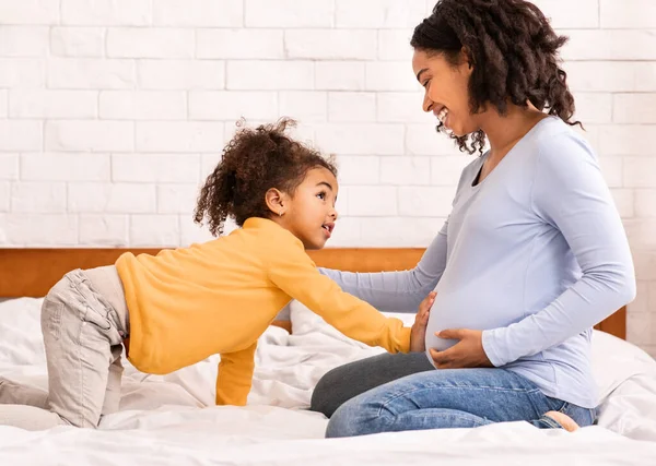 Lánya érintése Terhes anyák has ül az ágyon otthon — Stock Fotó