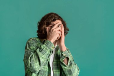 Endişe ve stres. Kıvırcık adam yüzünü korku içinde kapatıyor.