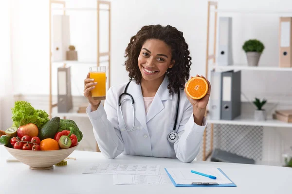 Χαρούμενη γυναίκα διατροφολόγος που κρατάει φρέσκο χυμό πορτοκαλιού — Φωτογραφία Αρχείου