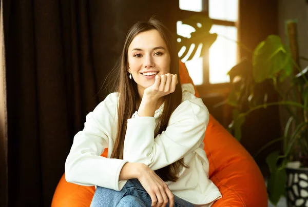 Hermosa chica milenaria en silla de bolsa en el interior del hogar — Foto de Stock