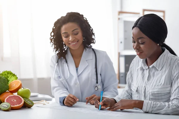 Joyeux nutritionniste africain aidant le patient avec la forme médicale — Photo