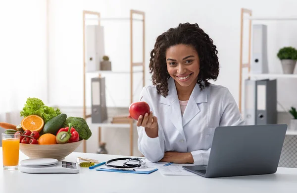 Atractivo médico mujer amablemente recomienda comer frutas frescas —  Fotos de Stock