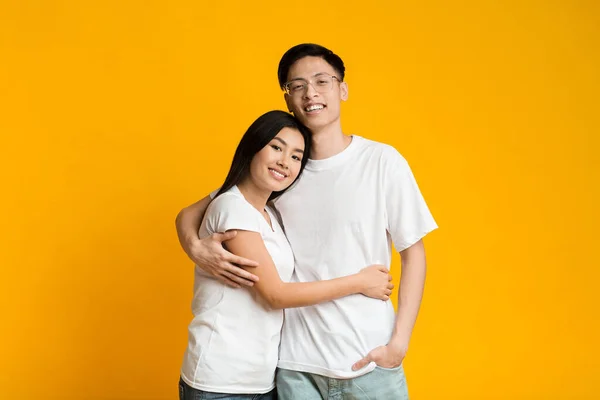 Azji słodkie para obejmując na żółtym tle — Zdjęcie stockowe
