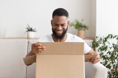 Evde online alışveriş. Gülümseyen adam paketi açıyor.