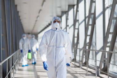 Koruyucu maskeli dezenfektan işçileri bakteri veya virüs püskürtür.