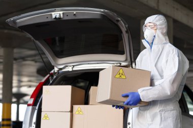 Koronavirüslü bir adam tehlikeli maddeden koronavirüsle kutuları boşaltıyor.