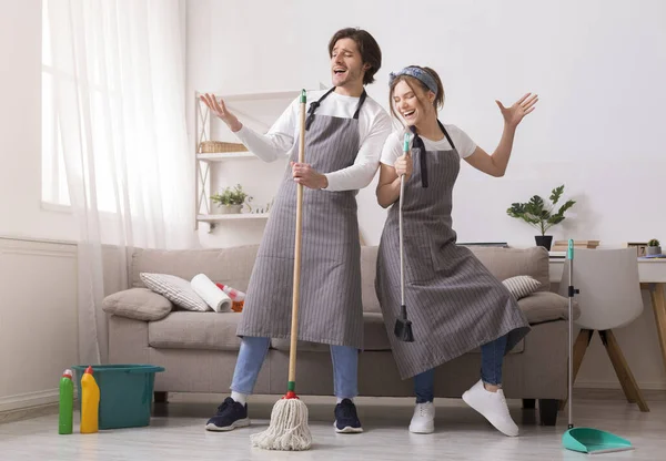 Casal se divertindo enquanto limpa casa, jogando com esfregona e vassoura — Fotografia de Stock