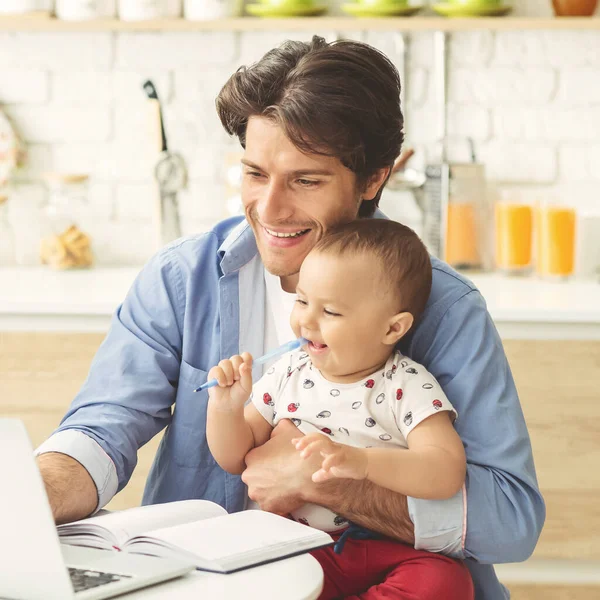 Great father working at home with baby son at kitchen — Stock Photo, Image