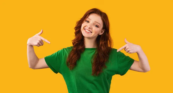 Χαμογελαστό κορίτσι με κόκκινα μαλλιά που δείχνει τον εαυτό της πάνω από το κίτρινο φόντο — Φωτογραφία Αρχείου