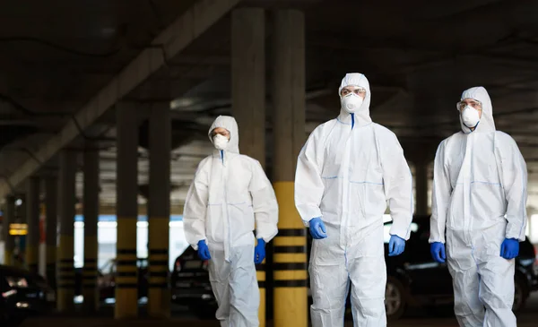 Doctors in virus protective suits on duty on public parking — Stock Photo, Image