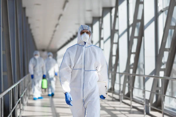 Desinfecterende werknemers in beschermende maskers en pak sprays bacterieel of virus — Stockfoto