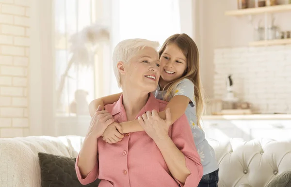 Familienbande. Schöne kleine Mädchen glücklich emracing ihre Oma im hellen Wohnzimmer — Stockfoto