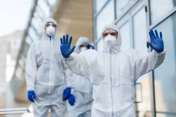 Hombre en traje de protección contra el virus que detiene multitud — Foto de Stock