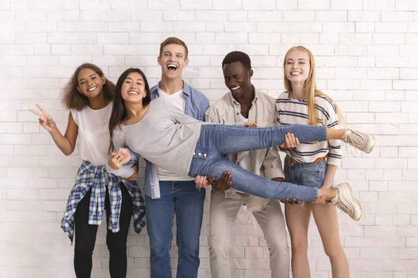 Vreugdevolle internationale groep vrienden poseren over witte muur — Stockfoto