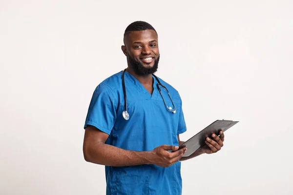 带着医疗报告笑着穿蓝色制服的黑人医生 — 图库照片