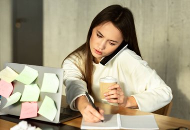 İş konseptinde birden fazla iş. Kadın telefonda konuşur, yazar ve kahve içer.