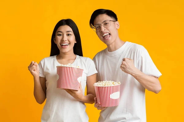 Emocjonalna azjatycka para ogląda film akcji, jedząc popcorn — Zdjęcie stockowe