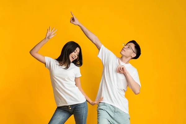 Émotionnel asiatique guy et fille danse sur jaune fond — Photo