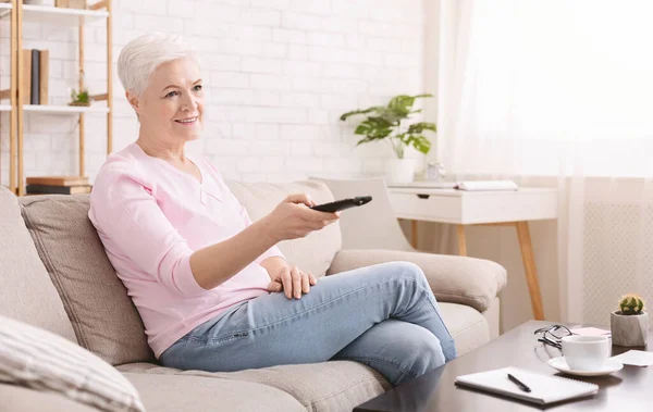 Klidná starší žena dívá na televizi doma — Stock fotografie