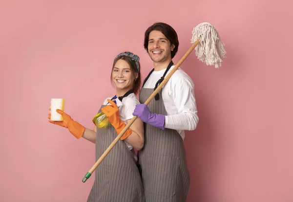 Servizio di pulizia team in grembiuli posa su sfondo rosa in studio — Foto Stock