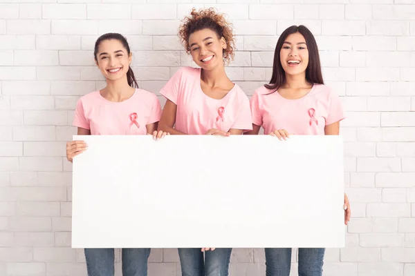 Tre ragazze volontarie multirazziali del cancro al seno che tengono bordo vuoto, Mockup — Foto Stock