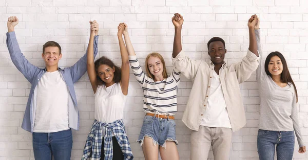 Felices amigos de pie sobre la pared de ladrillo blanco, uniendo las manos —  Fotos de Stock