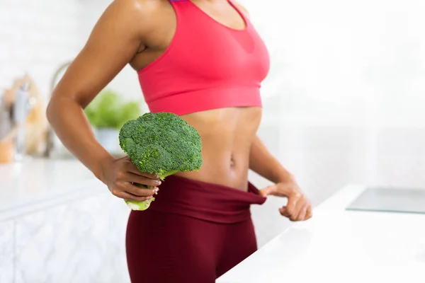 Fit Afro-Mädchen in übergroßen Hosen mit Brokkoli — Stockfoto