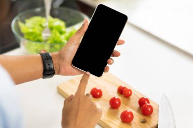 Afro kız mutfakta boş ekranlı akıllı telefon kullanıyor.