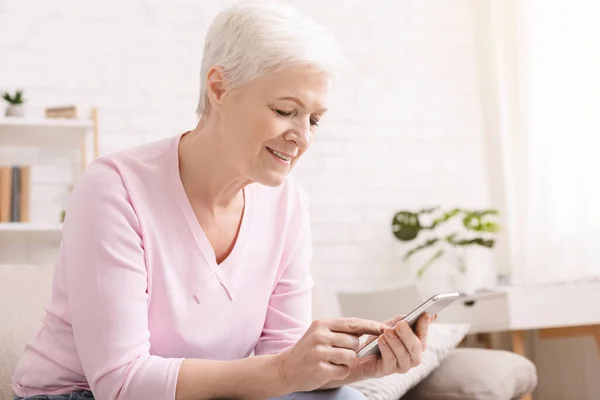 Senior žena chatování na smartphone s rodinou doma — Stock fotografie