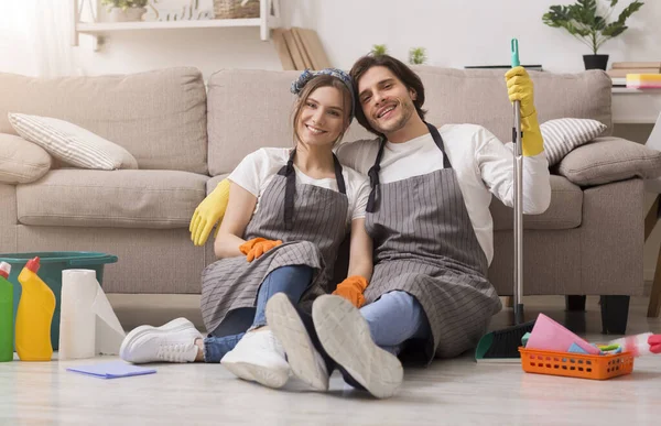 Retrato de casal feliz sentado no chão após a limpeza da primavera em casa — Fotografia de Stock