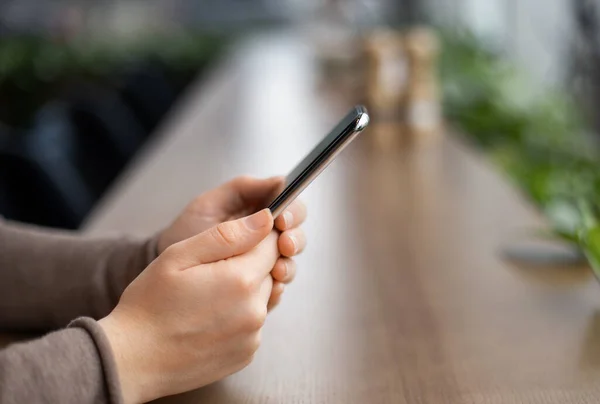 Female hands holding cell phone watching video during coffee break — Stock Photo, Image