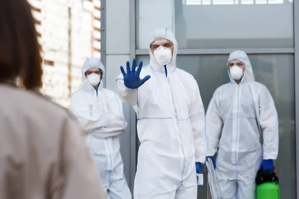 Men in coronavirus suits gesturing woman to stop — Stock Photo, Image