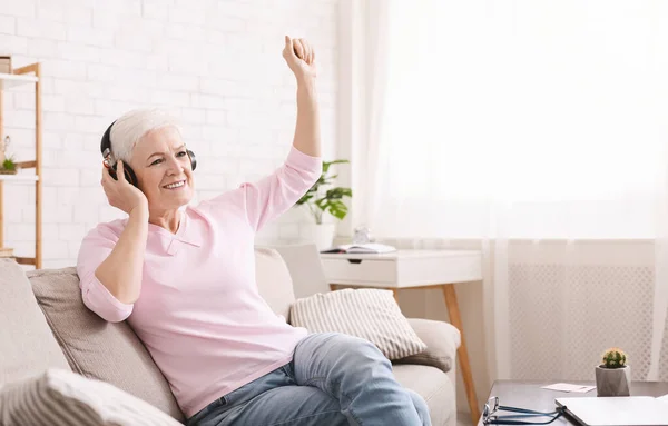 Alegre señora mayor disfrutando de la música en nuevos auriculares en casa —  Fotos de Stock