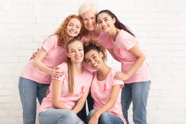 身穿带粉红带T恤的志愿者们拥抱在白墙之上 — 图库照片