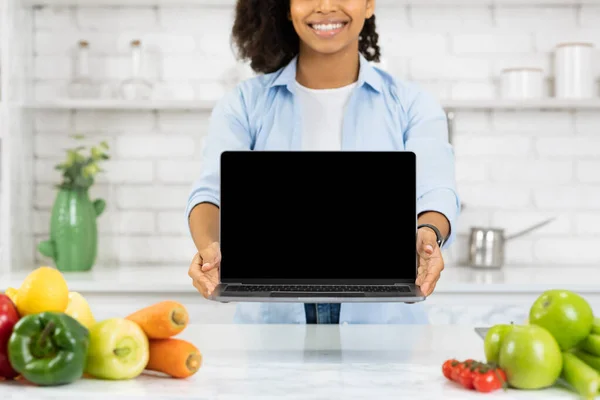 Невпізнавана чорна дівчина тримає ноутбук на кухні — стокове фото