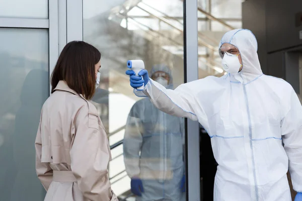 Pria di coronavirus hazmat mengukur suhu seorang wanita — Stok Foto