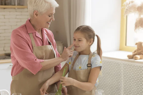 Веселий час для випічки. Щаслива старша леді торкається її онуки ніс на кухні, порожній простір — стокове фото