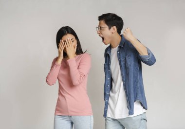 Vahşi Asyalı bir adam kız arkadaşını dışarıda yumruğuyla tehdit ediyor.