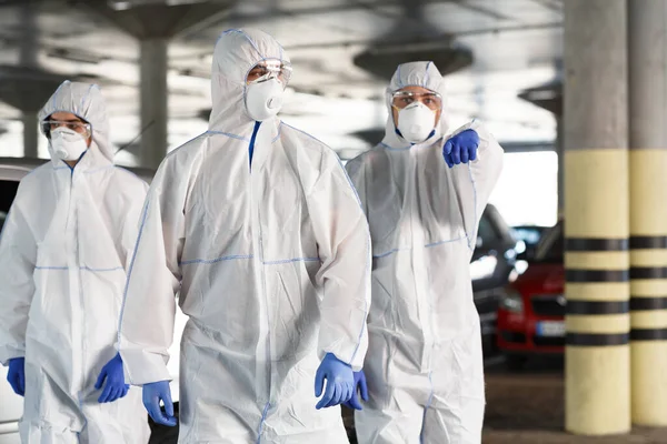 Hombres con trajes de materiales peligrosos apuntándote, epidemia, cuarentena — Foto de Stock