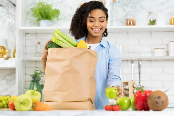 Довольная черная девушка держит бумажный пакет с едой — стоковое фото