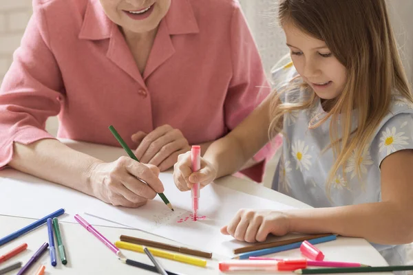 Mature woman with her lovely granddaughter drawing Christmas tree together in kitchen — Stock Photo, Image