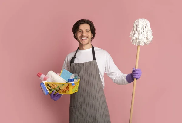 Millennial Man pozowanie z mopem i środki czyszczące na różowym tle — Zdjęcie stockowe