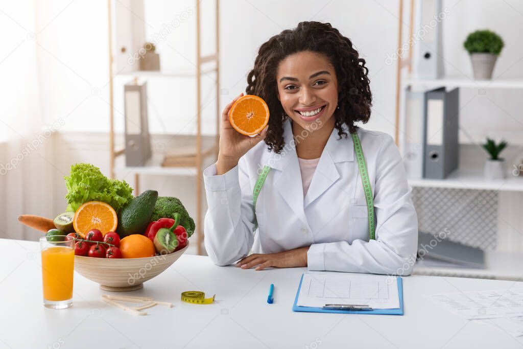 Modern dietologist african woman recommending fresh oranges