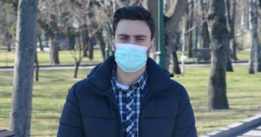 Şehir parkında koruyucu sağlık maskesi takmış genç bir adam