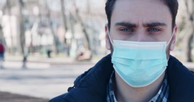 Şehir parkında duran tıbbi koruyucu maskeli adam.