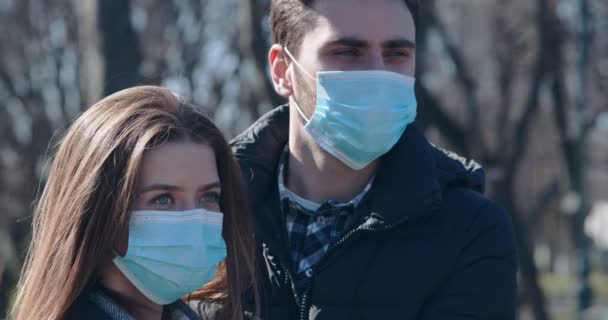 Jong paar staan buiten in beschermende maskers — Stockvideo