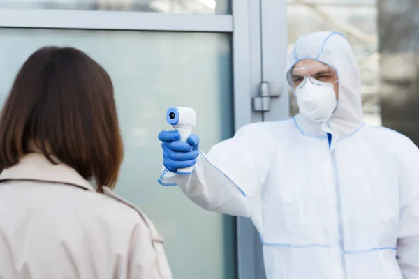 Hombre en materiales peligrosos utilizando termómetro infrarrojo para comprobar la temperatura —  Fotos de Stock