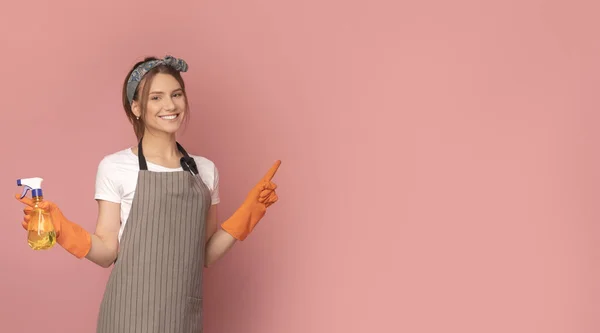 Lächelnde Frau in Schürze hält Sprayer in der Hand und zeigt auf Kopierraum — Stockfoto