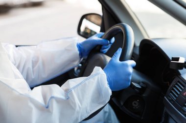 Coronavirus hazmat ve eldiven giyen biri araba kullanıyor.